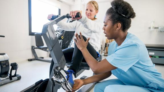 A physiotherapist instructing a patient how to use a cycling machine.