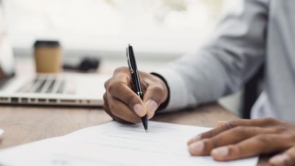 Someone signing a form with a pen.