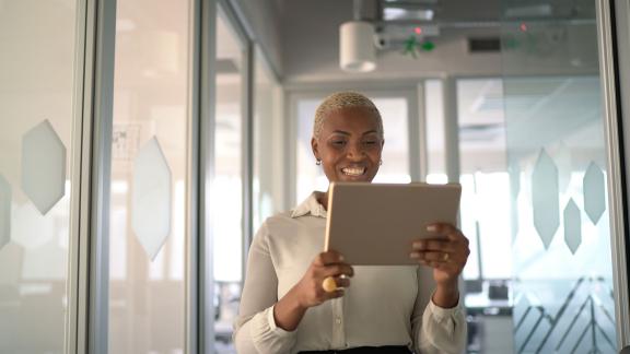 An office worker holding a tablet during a video call.