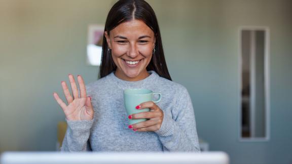 A home worker on a video call, waving.