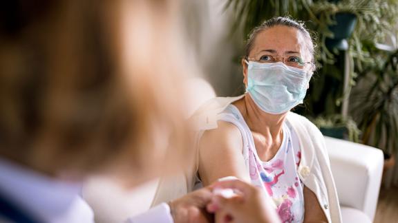 A woman in a face mask receiving a COVID-19 vaccination.