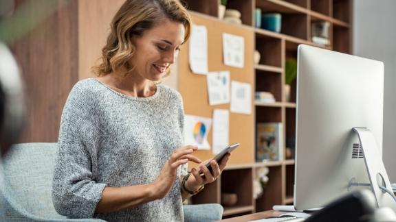 Photo of a business woman using smartphone while working