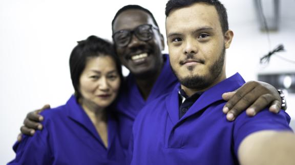 Photo of three people from different backgrounds smiling