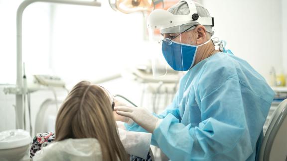 A dentist in PPE, mid-appointment.