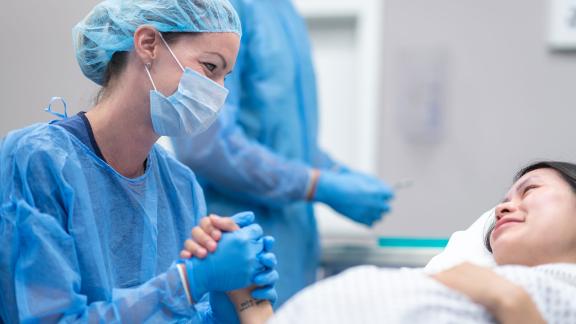 A midwife holding a patient's hand.