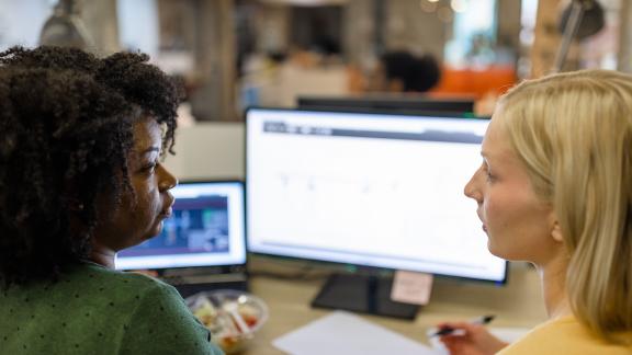 Two office workers having a meeting at a desk.