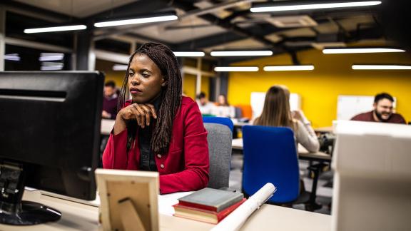 An officer worker at their desk in a busy open-plan office