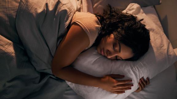 A woman asleep, clutching a pillow.