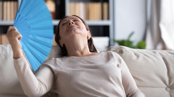 A woman cooling herself down with a hand fan.