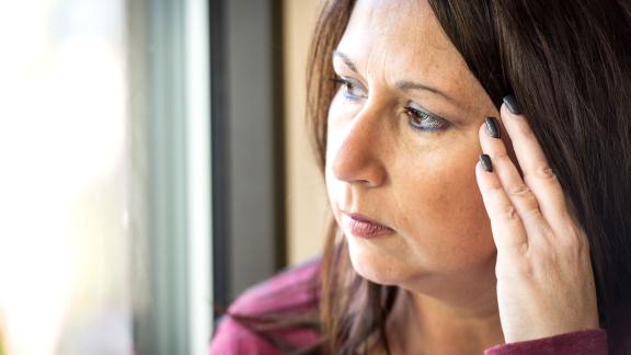 A woman touching her head as if in pain.