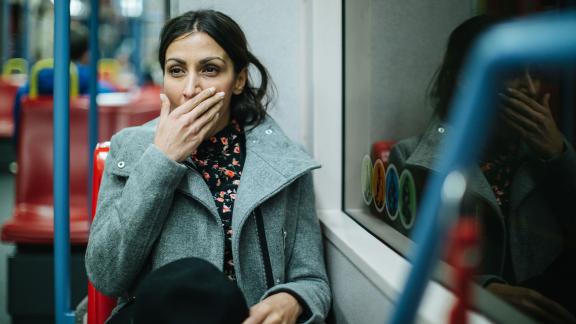 A woman on a bus, yawning.