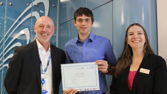Kieran from HHFT standing between two staff members receiving a certificate