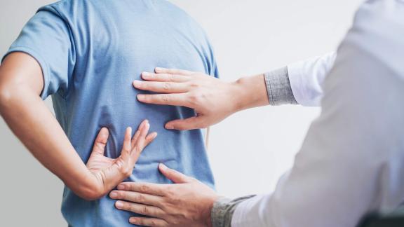 Persons arms and hands examining another persons wearing a blue tshirt back.