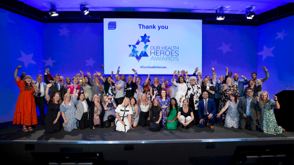 A large group of delegates posing for a picture on the stage of the Our Health Heroes Awards