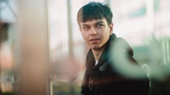 A young person in a brightly-lit corridor.