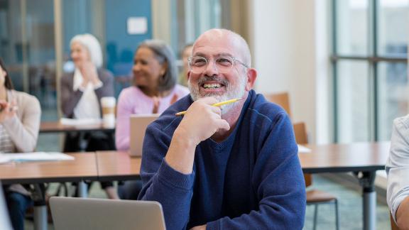 A smiling, thinking man, taking part in a webinar.