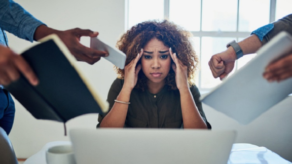 lady holding her head being stressed as many people are trying to get her attention