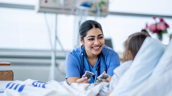 A smiling doctor chatting to a patient who is in bed.