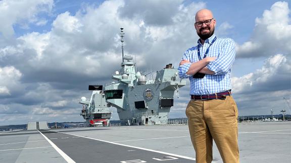 Luke Clifford-Roper-Smith standing in civilian clothes on the UK aircraft carrier HMS Prince of Wales.