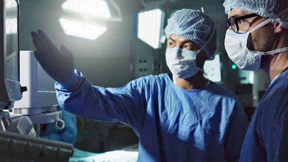 Surgeons discussing while looking at a screen