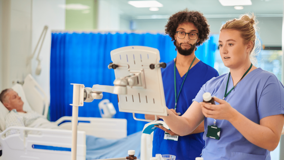 Two nurses reviewing medical equipment in a hospital setting