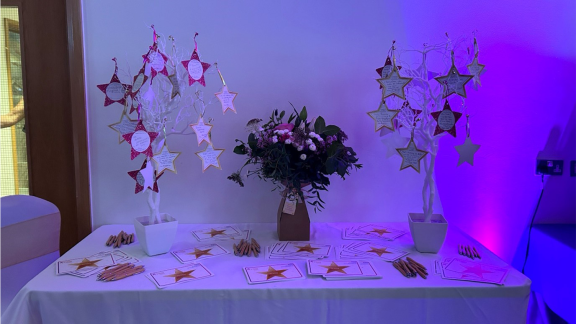 A picture of a table with some flowers on and a fake tree with stars hanging from it