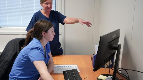 Health T Level student at a computer taking direction from a supervisor