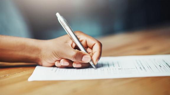 A hand ticking a survey with a pen.