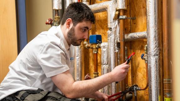 A student working with tools mending pipework