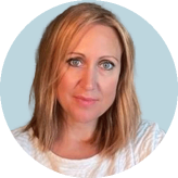 Headshot of Sarah Hirst wearing a white top and gold necklace, with shoulder-length blonde hair, against a blue background.