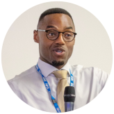 Headshot of Marcus Riddell, speaking into a microphone