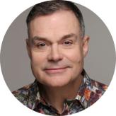Headshot of a man, smiling, wearing a brightly coloured shirt