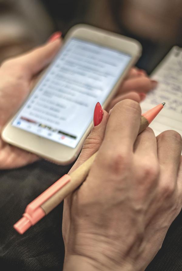 A delegate making notes on a phone and notepad. 