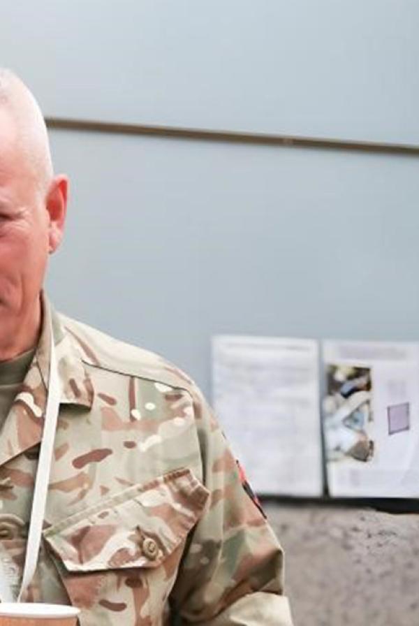 Three service personnel in uniform speaking with a civilian at a conference.