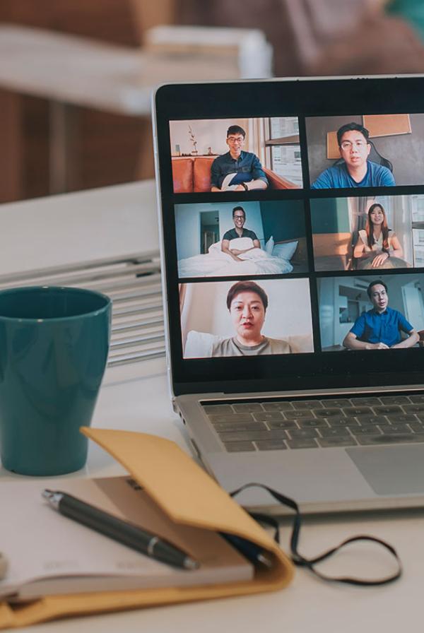 A laptop on a desk with a conference call on-screen.
