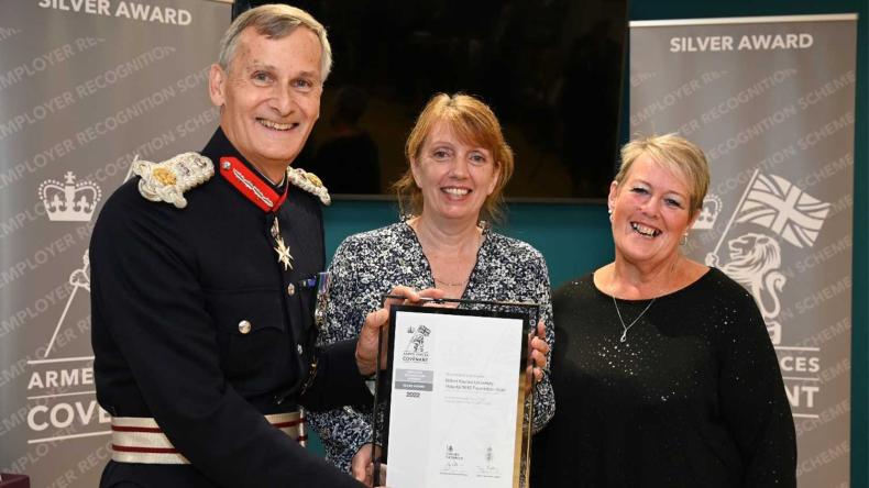 Armed forces personnel being presented with a framed certificate at an event.