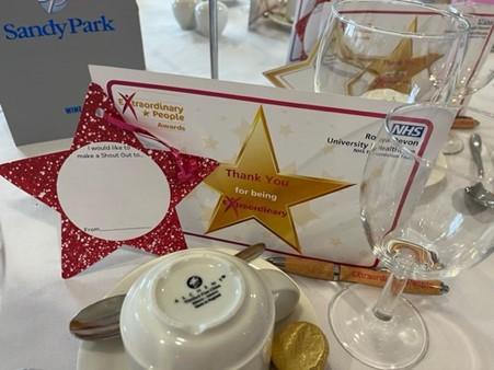 A close up of a table setting that has a cup, a certificate of recognition and a glass