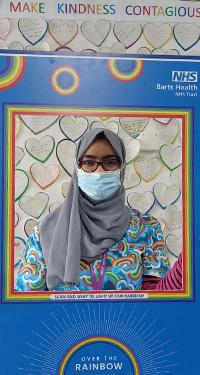 Nurse holding a cardboard cutout of Over The Rainbow at NHS Barts Trust. Above the image quotes "Make kindness contagious".